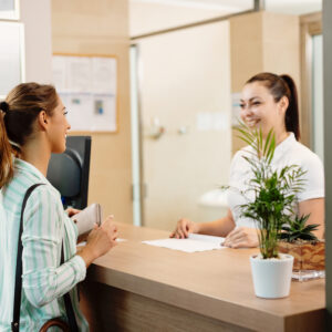 Young happy woman checking in health spa and communicating with a receptionist.